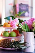 Tulips in pink ceramic jug next to cake stand of fruit