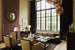 Elegante Sessel und Sofa in hohem Wohnzimmer mit Sprossenfenster und Poulsen Hängeleuchten