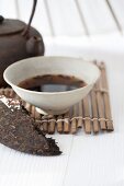 An arrangement featuring a tea brick and brewed pu-ehr tea in a tea bowl