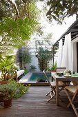 Table and chairs in front of wood-edged pool in courtyard