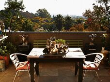 Terrasse mit Holztisch und Metallstühlen, Blick über tropische Landschaft