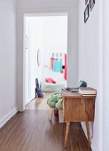 Restored fifties sideboard in hallway; view of pouffe and coat rack through open door in background in period apartment