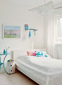 Dekorative Siebdruckkissen auf Bett mit weisser Tagesdecke, Designer Nachtisch und dänische Leuchte neben Erinnerungsfoto
