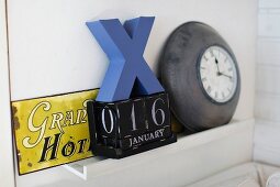 Vintage arrangement of old enamel sign, perpetual calender and clock on shelf