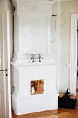 Antique, white fireplace with copper door and two candlesticks on mantelpiece in traditional interior