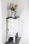 Jug of flowers on free-standing, vintage kitchen stove in corner