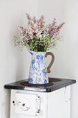 Bouquet in vintage jug on old kitchen stove in corner