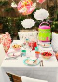 Party table set with brightly patterned plastic and paper tableware in garden