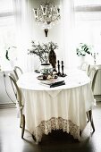Table with white tablecloth and chairs with curved backrests in rustic dining room