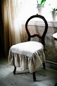 Antique chair with curved backrest and seat cushion with frill