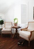 Stil-Sessel in Naturfarben und Beistelltisch aus Korbgeflecht vor Fenster mit innenliegenden Klappläden
