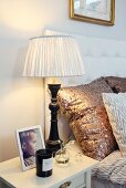 Table lamp with black-painted base and pleated lampshade on bedside table