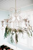 Chandelier festively decorated with thin garlands of twigs and crystals in Scandinavian house