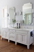 Weisser Waschtisch mit zwei Waschbecken, an Wand zwei Spiegel mit Leuchten