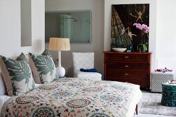 Doppelbett mit gemusterter Tagesdecke und Kissen mit Blattmuster im Landhausstil, Schlafzimmer mit Bad Ensuite
