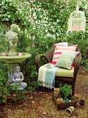 Wicker armchair, classic stone fountain and Buddha figurine next to climber-covered wall in garden