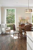 Antique, Rococo-style chairs and dining table; armchair next to open terrace door in background