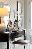 Plexiglas chair at antique, dark-wood dressing table with table lamp with pale lampshade
