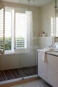 Detail of modern bathroom, partially visible washstand and glazed shower area next to window