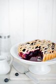 A sliced blueberry pie on a cake stand