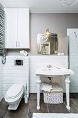 Washstand with white, turned legs against half-height tiling on wall and grey floor tiles