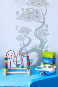 Toys on blue table against wall with stencilled tree motif