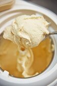 Home-made toffee ice cream on a spoon above an ice cream maker