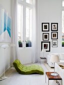 Green futon chair flanked by standard lamps opposite modern table lamp on delicate side table