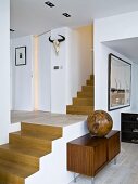 Wooden sphere on fifties-style sideboard against open staircase, view into hallway and hunting trophy on wall