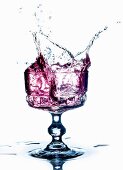 A purple drink splashing from a glass