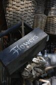 An old wooden basket with a label and a stack of wicker baskets