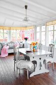 Comfortable, feminine living-dining area in white interior of Swedish country house with natural wooden floor