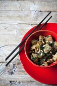 Fried Japanese turnips with leaves and seeds in a red bowl