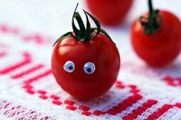 A tomato with eyes on a rustic tablecloth