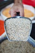 A hand holding a scoop of bulgar wheat at a market stall