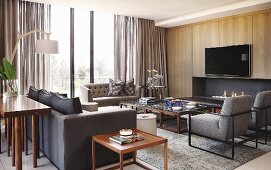 Sofa set around coffee table and side table; flatscreen TV above fireplace in wood-clad wall