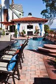 Chairs at cropped table with swimming pool in the background; Laguna Niguel; California; USA