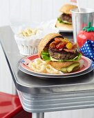 Two bacon cheeseburgers with onion rings and tomatoes