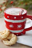 Hot chocolate in a red and white cup served with white chocolate biscuits