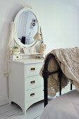 Crocheted blanket draped over foot of bed, vintage, white dressing table with oval mirror