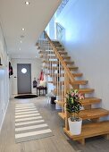 Contemporary foyer with cloakroom area, fitted wardrobes, pale wooden staircase and grey and white rug on tiled floor