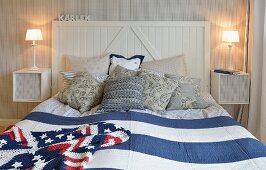 Double bed with wooden headboard, blue and white striped bedspread and Stars and Stripes blanket