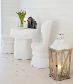 Chairs and tables carved from thick tree trunks, painted white and decorated with lettering and vintage candle lantern in foreground