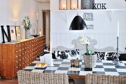 Chequered table and decorative letters in country-house kitchen-dining room; vintage apothecaries' cabinet in background