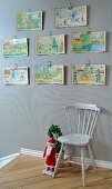 Colourful children's drawings above traditional wooden chair next to Father Christmas figurine at head of staircase