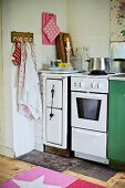 Solid-fuel stove, cooker and tea towels hanging from wall hooks in corner of kitchen