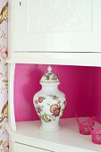 White corner cabinet with interior walls of shelf painted hot pink