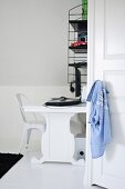 Blick durch offene Tür auf schwarz-weiße Schreibtischecke mit weißem Designerstuhl und Retro Wandregal