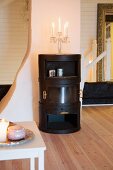 Candelabra on black, wood-burning stove in renovated, white attic room with plain wooden floor