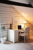 Vintage-style home office below wood-clad sloping ceiling; gable-end wall made from whitewashed wooden beams